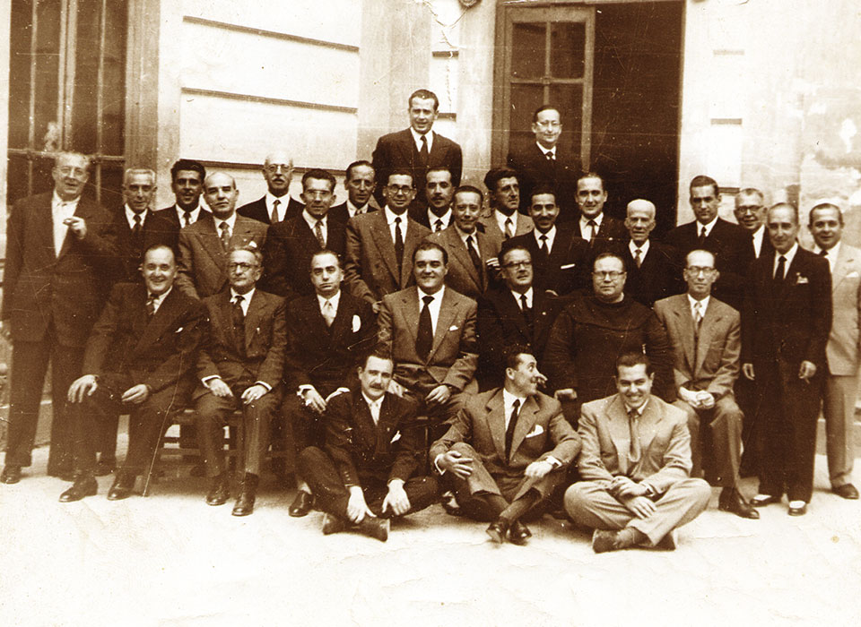 Colegiados a principios de los años 50, en el Casino de Ciudad Real, frente a los jardines del Prado. Autor: Matos (ver FORO nº 71). Entre otros: De pie, fila superior, de izquierda a derecha: Ismael López de Sancho y Ricardo Torquemada. De pie fila inferior, de izquierda a derecha: Juan Ignacio Morales (1º), Eduardo Messía de la Cerda (2º), Manuel Rivero (3º), José M.ª Martínez Val (4º), Zoilo Benítez (último lugar). Sentados, fila superior, de izquierda a derecha: Díaz Vivanco, Presidente de la Audiencia Provincial (3º), José María del Mozal (4º), Carlos Calatayud Gil (5º), Antonio Mayor, Fiscal (6º). Sentados, fila inferior, de izquierda a derecha: Carlos Calatayud Maldonado, Tomás Valle, José Luis Barragán.